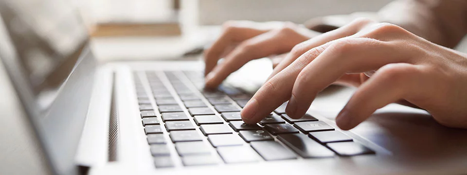 Close-up of hands typing on laptop keyboard